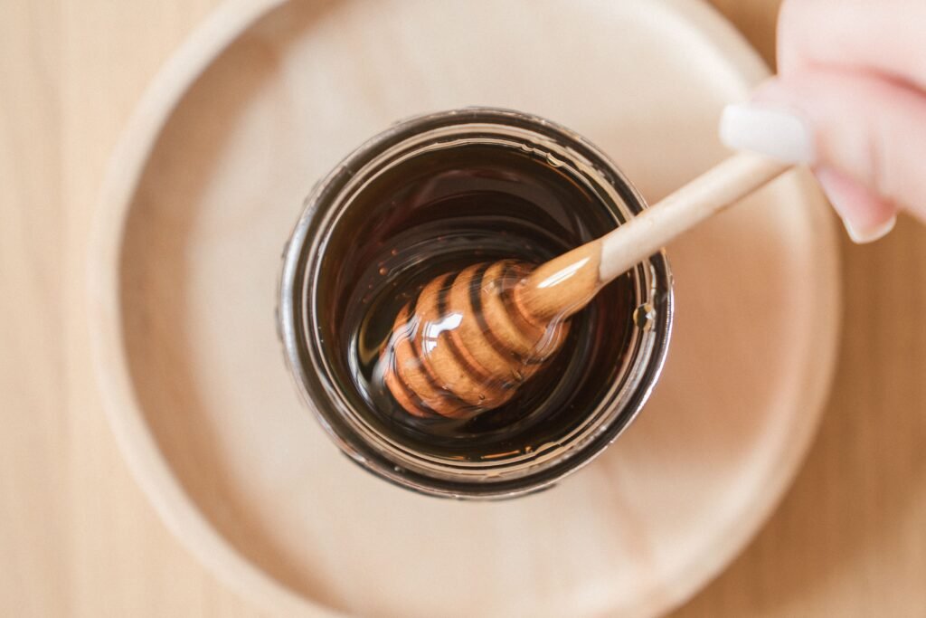 Miel sin filtrar con una cuchara de madera de miel dentro de un tarro